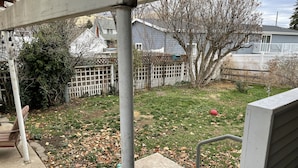 A residential backyard with a concrete patio, a white fence, and a tree. - Cozy 2+bed/1bath in quiet neighborhood (Pomeroy)