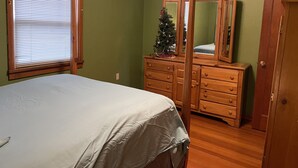A bedroom with a bed, a dresser, a mirror, a Christmas tree, and a door. - Cozy 2+bed/1bath in quiet neighborhood (Pomeroy)