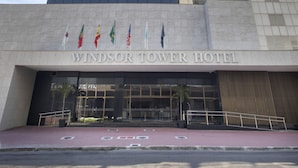 Hotel Windsor Tower con fachada de vidrio moderna, una entrada destacada y banderas visibles en el exterior.