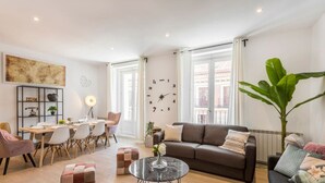 Un salon moderne comprenant un canapé, une table basse et un coin repas avec des chaises et une table.