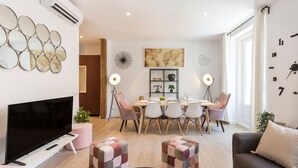 Un salon moderne avec un téléviseur à écran plat, une table basse et un canapé. Il y a également un coin repas avec une table et des chaises.