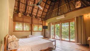 A spacious bedroom with a large bed, wooden flooring, a ceiling fan, and a view of the outdoors. - Senda Watapuy (Santa Marta)