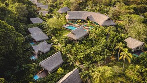A resort with thatched-roof huts, swimming pools, and lush tropical vegetation. - Senda Watapuy (Santa Marta)