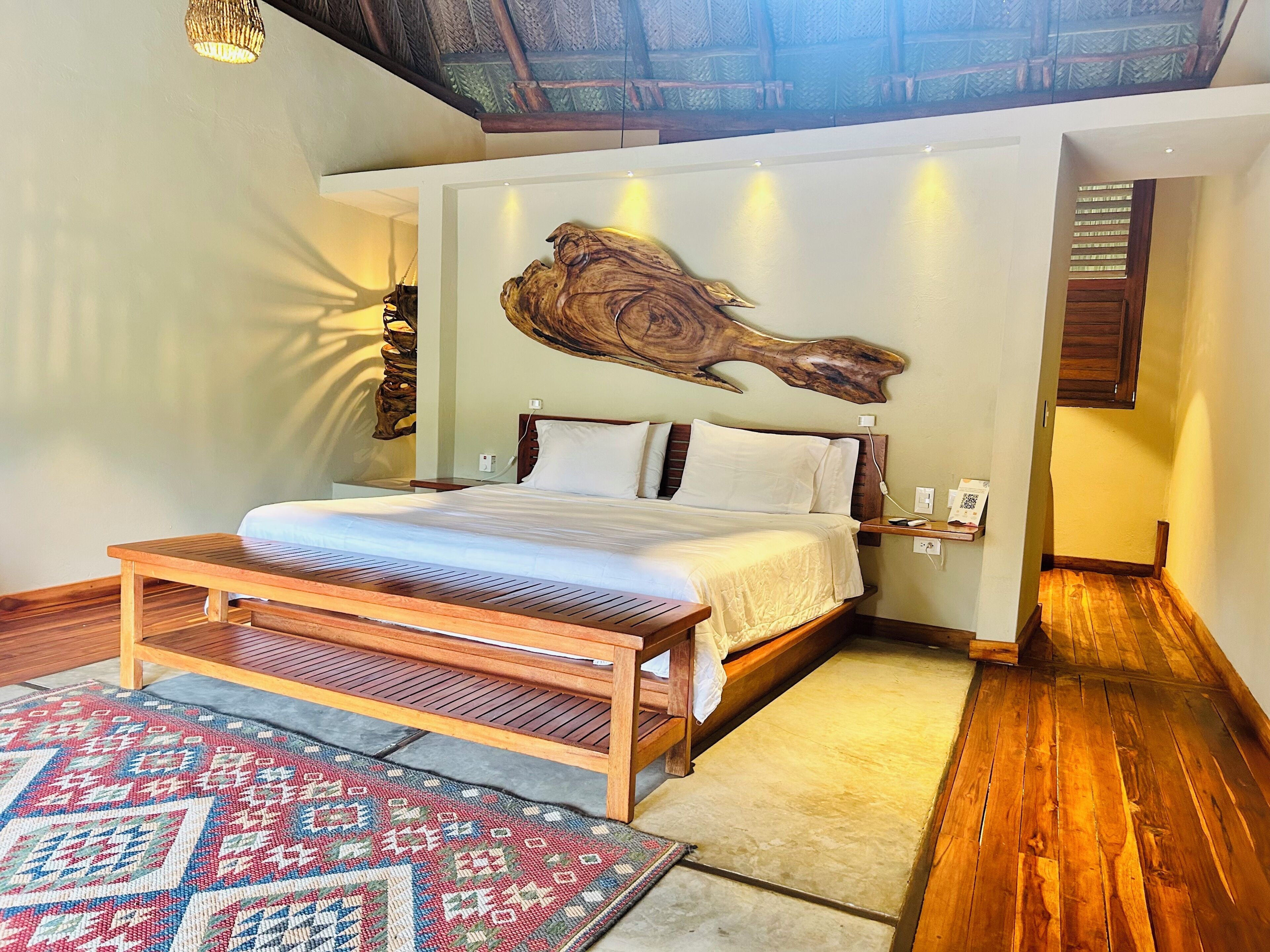 A bedroom with a wooden bed, a large wall art piece, a bedside table, and a patterned rug.