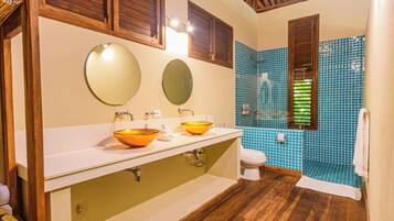 A bathroom with two sinks, a toilet, and a shower area.