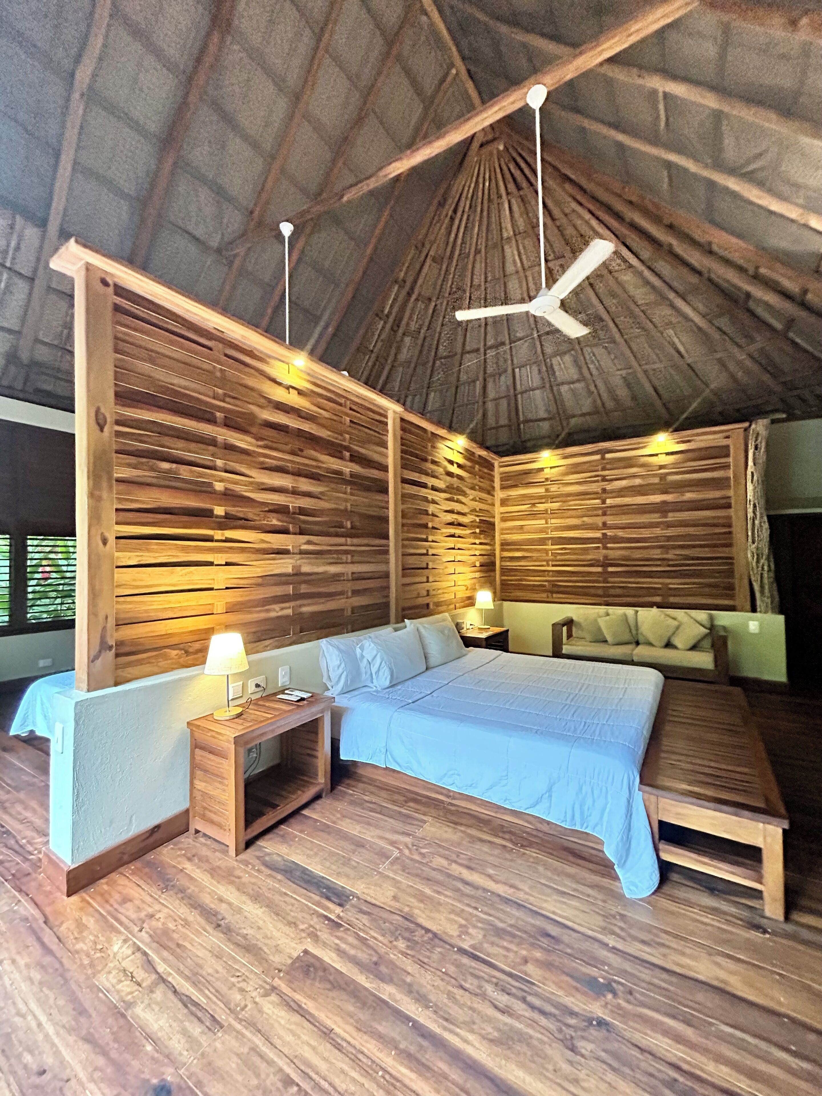 A room with a bed, bedside tables, a ceiling fan, and wooden walls.