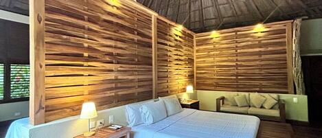 A room with a bed, bedside tables, a ceiling fan, and wooden walls.