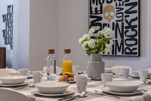 A breakfast table set with white plates, cups, and a vase of white flowers. There are two bottles of water and a bottle of orange juice. - PLAZA MAYOR by MONARO***** (Madrid)