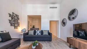 A modern living room with a grey sofa, a wooden coffee table, and a TV on a wooden stand. - PLAZA MAYOR by MONARO***** (Madrid)