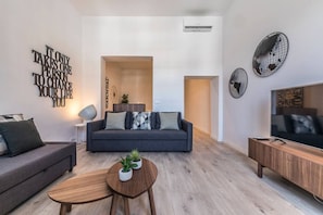 A modern living room with a grey sofa, a wooden coffee table, and a TV on a wooden stand.