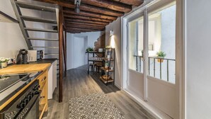A modern kitchen with a wooden ceiling, a built-in stove, and a dining area with a staircase leading to a balcony. - PLAZA MAYOR by MONARO***** (Madrid)
