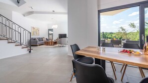 A modern living space with a dining area, a staircase, and a view of greenery. - Charming 4BR Villa with Private Pool and Nature Views (Vabriga)