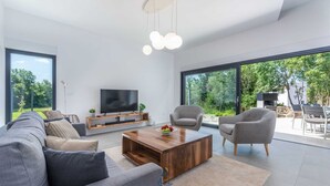 A modern living room with a large TV, comfortable seating, and a wooden coffee table. - Charming 4BR Villa with Private Pool and Nature Views (Vabriga)