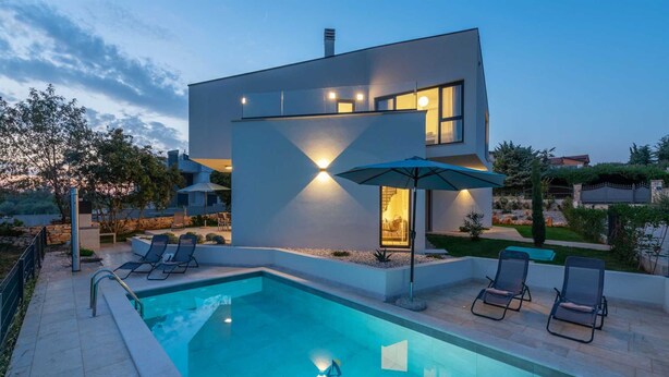 A modern two-story house with a swimming pool, outdoor seating, and a well-lit patio area. - Charming 4BR Villa with Private Pool and Nature Views (Vabriga)