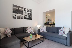 A modern living room with a grey sofa set, a coffee table, and a cityscape wall art.