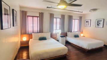 A hotel room with two beds, a ceiling fan, and a small seating area.