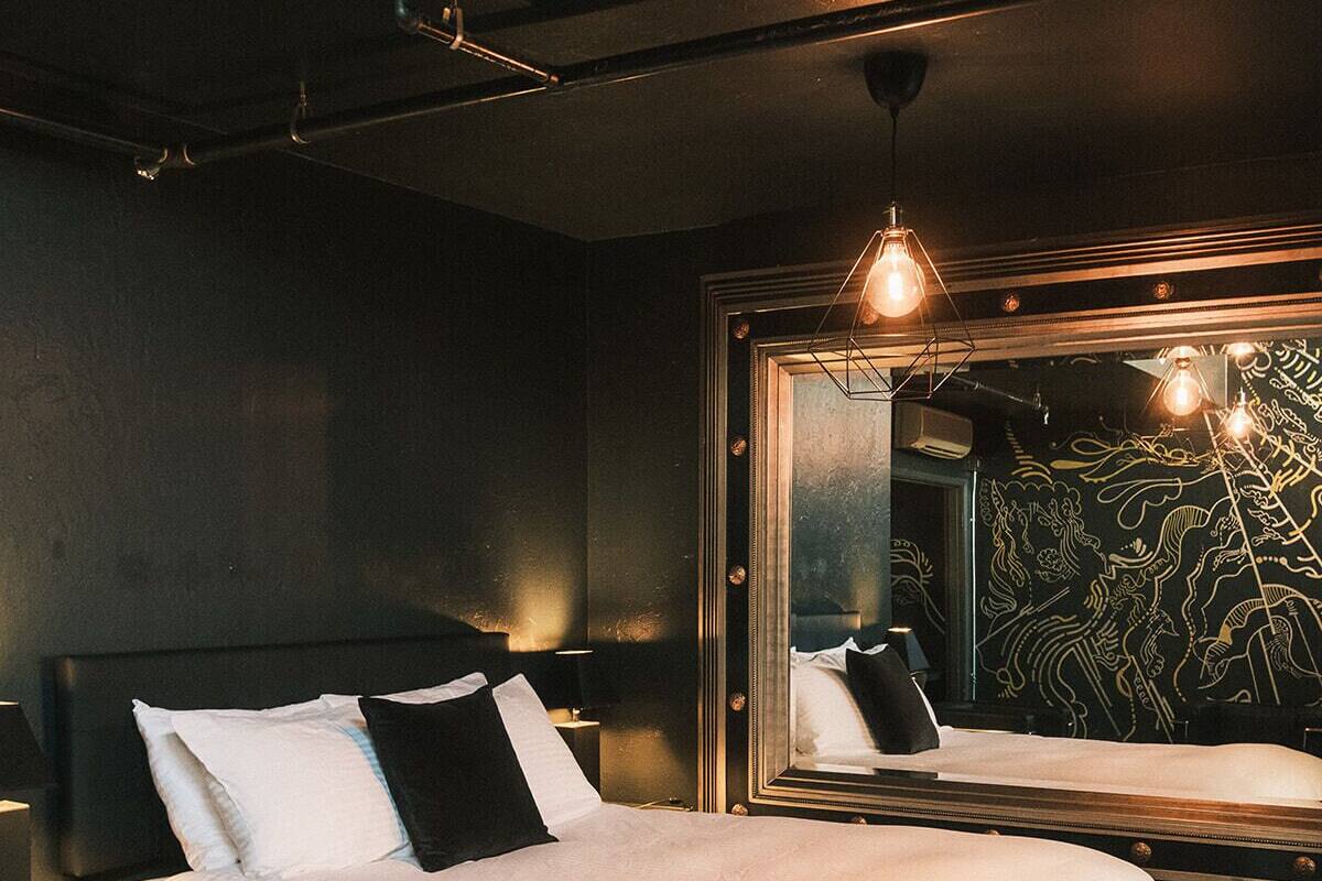 A modern bedroom with a large bed, a nightstand, a mirror, and a wall with a decorative pattern.
