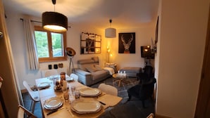 Un'accogliente zona pranzo con un tavolo apparecchiato per due, un divano e una televisione sullo sfondo.
