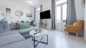 Een moderne woonkamer met een grijze bank, een ronde salontafel en een gele fauteuil.