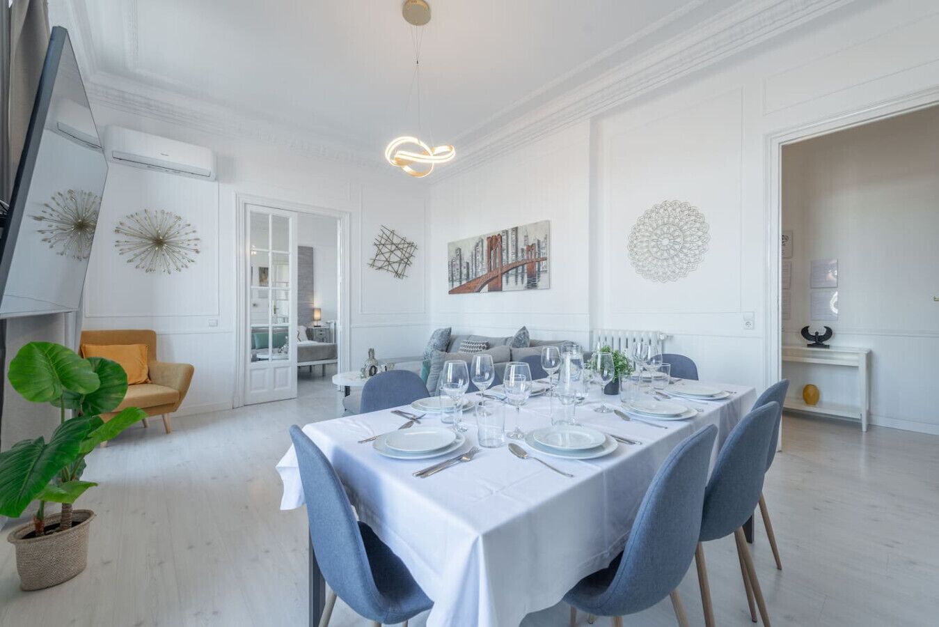 A dining area with a white table set for four, surrounded by chairs.