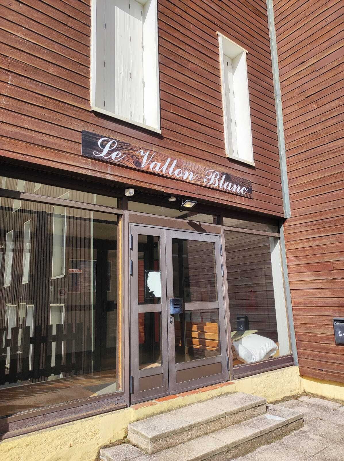 Un edificio de madera con un letrero que dice "Le Vallon Blanc".