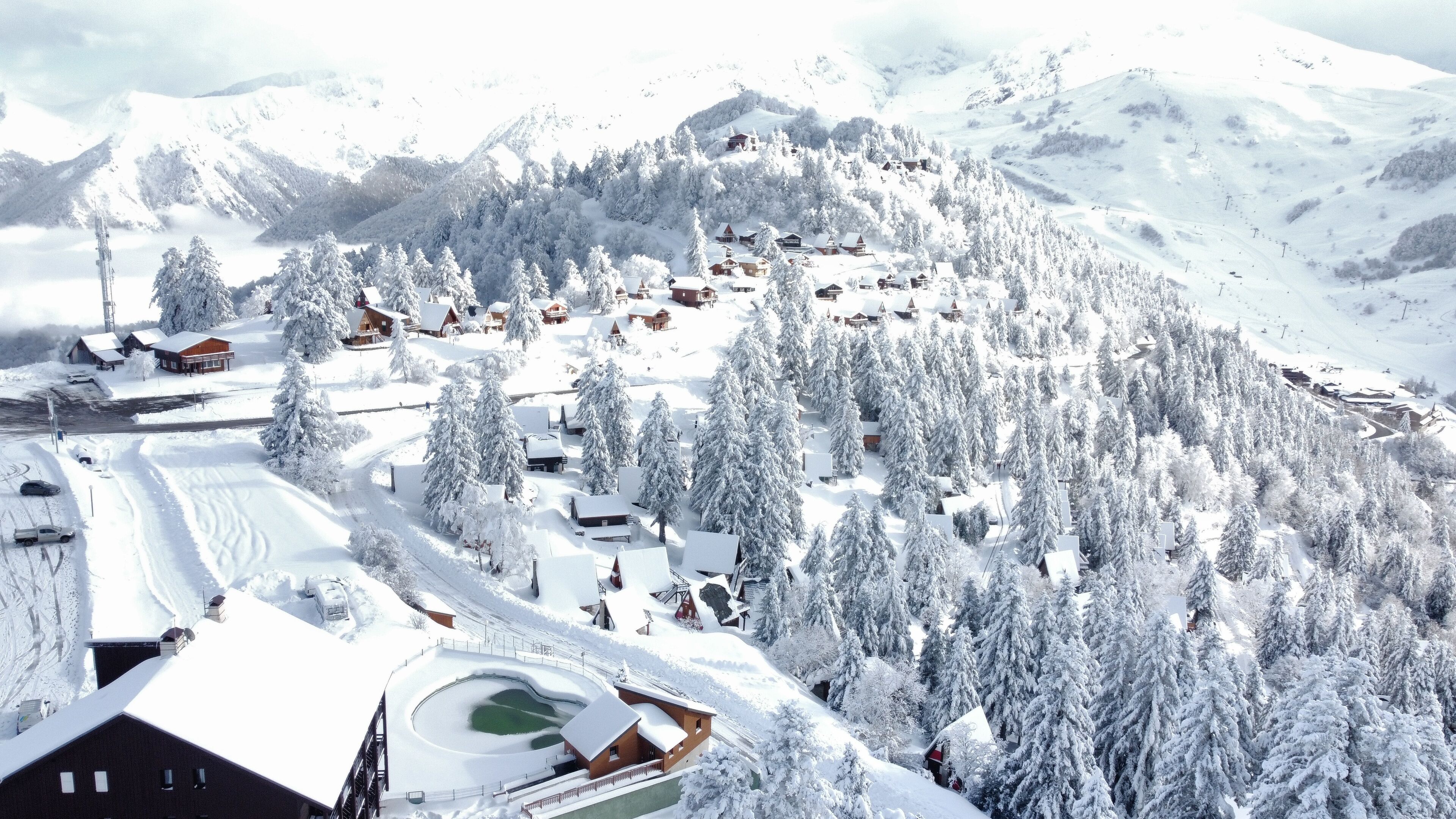 Un pueblo cubierto de nieve en la montaña con cabañas de madera y una pista de esquí.