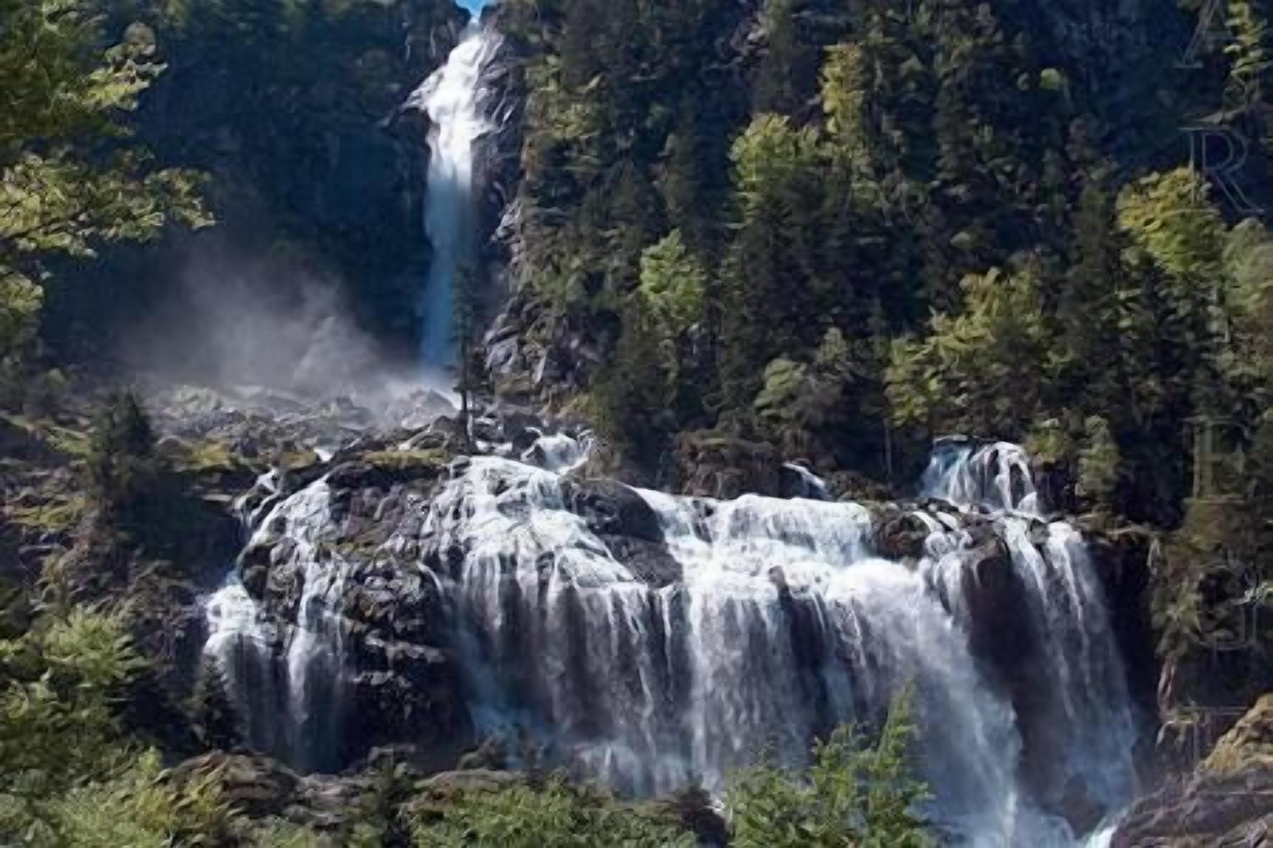 Une cascade d’eau se déversant sur des rochers, le tout étant entouré d’une forêt dense.