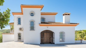 Un edificio blanco con techo de tejas, varias ventanas y una entrada central en arco.