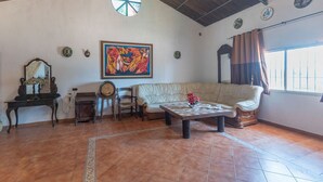 A living room with a sofa, a coffee table, a clock, and a painting on the wall.