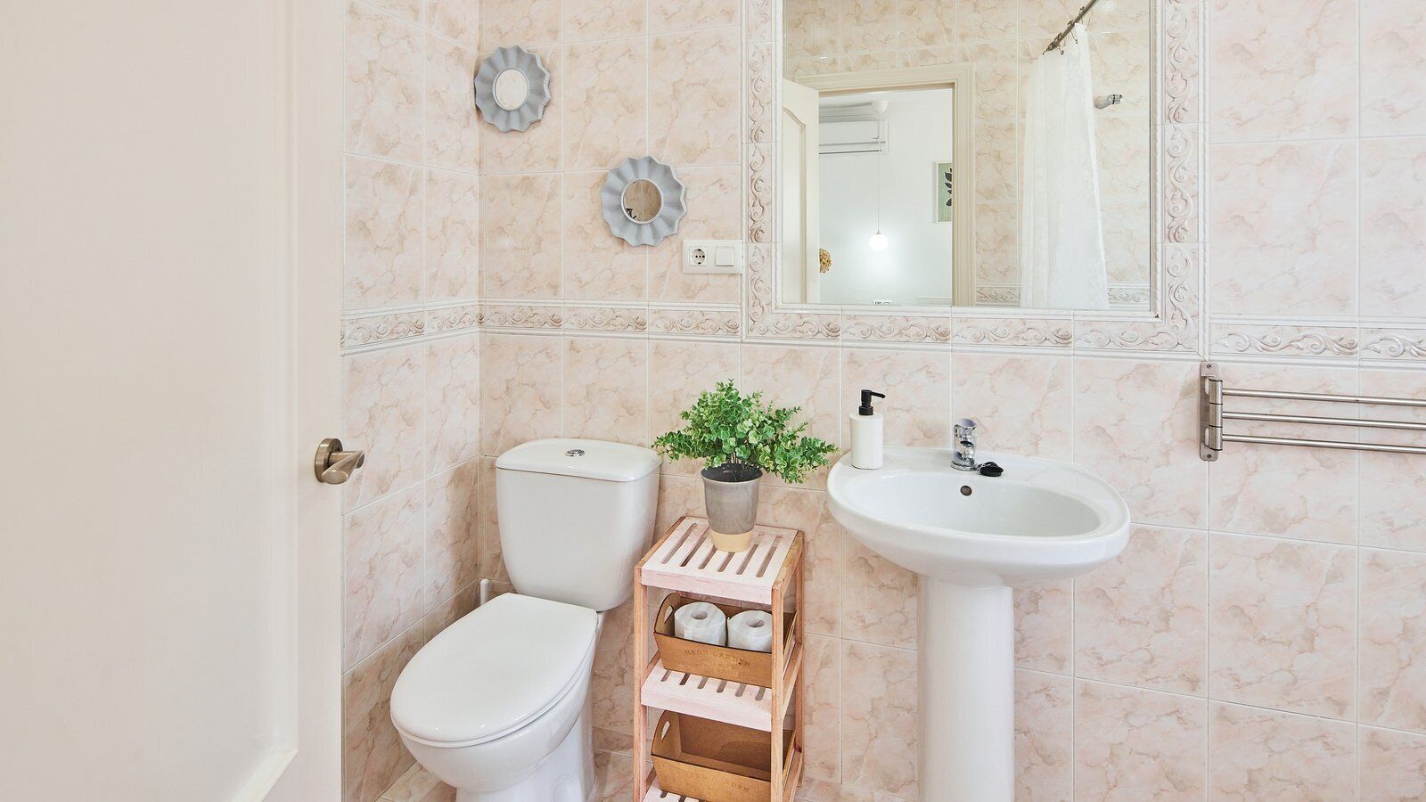 Ein Badezimmer mit Toilette, Waschbecken und einem dekorativen Spiegel.
