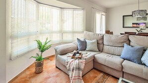 Ein Wohnzimmer mit einem beigefarbenen Sofa, einem Couchtisch und einer Topfpflanze.