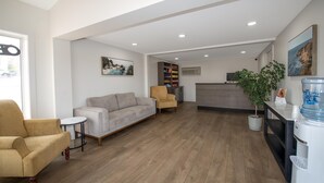 A spacious living area with a sofa, armchairs, a small table, and a bookshelf.