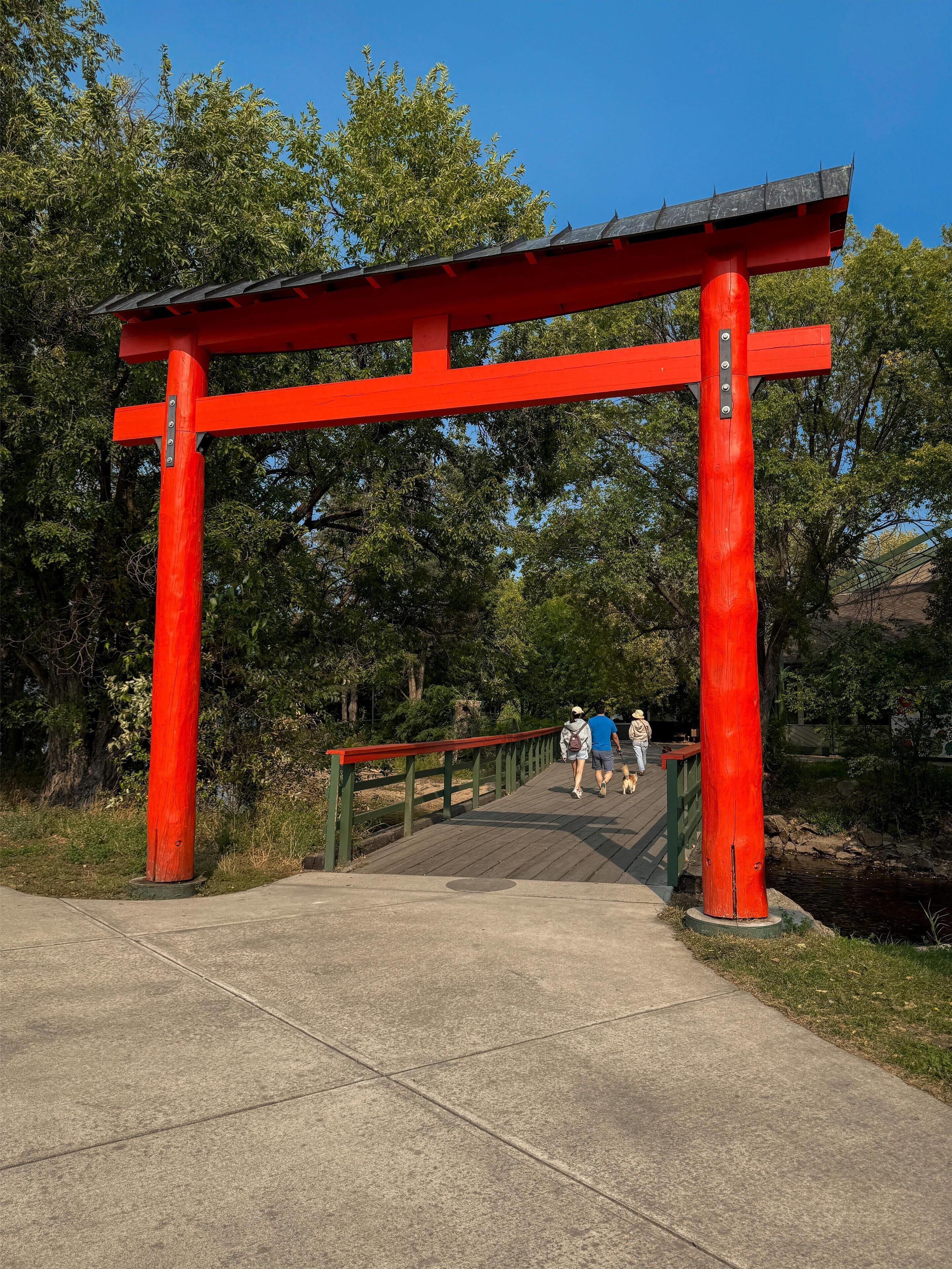 Un torii rojo a la entrada de un parque con un paseo de madera.