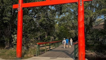 Un torii rojo a la entrada de un parque con un paseo de madera.