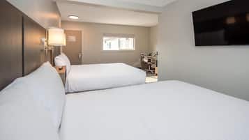Una habitación de hotel con dos camas, un escritorio, una silla, un televisor y una ventana.