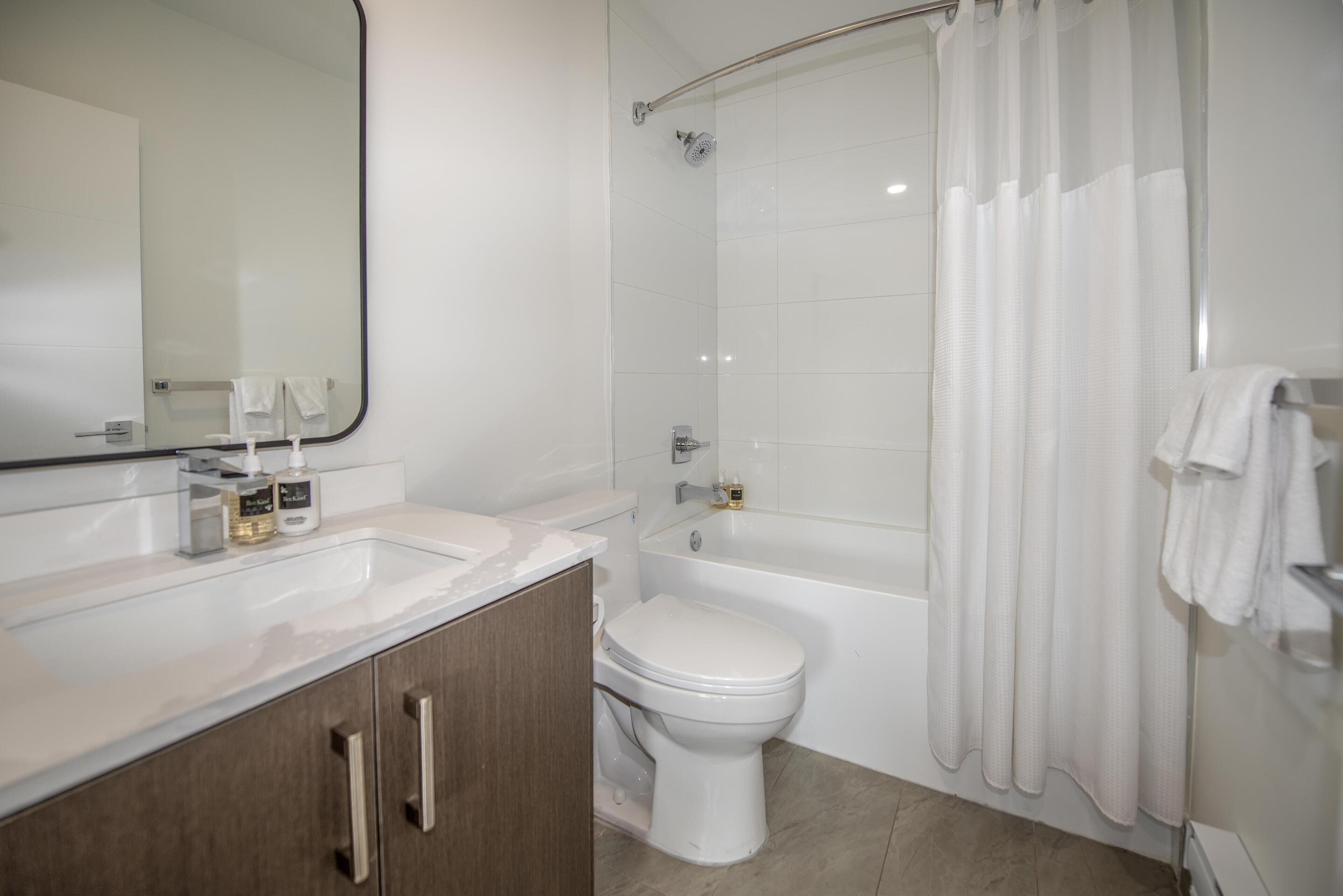 A modern bathroom with a white sink, toilet, and bathtub.