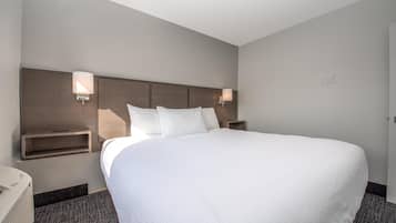 Una habitación de hotel con una cama grande, dos mesitas de noche y lámparas de pared.