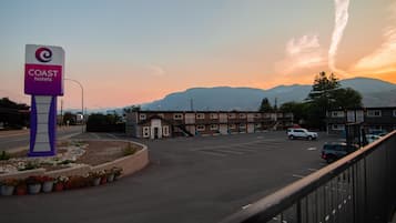 A motel with a sign for 'COAST hotels', a parking lot, and a mountain in the background.