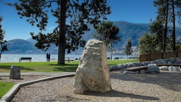 Un parc avec un grand rocher, des bancs et une vue sur un lac.