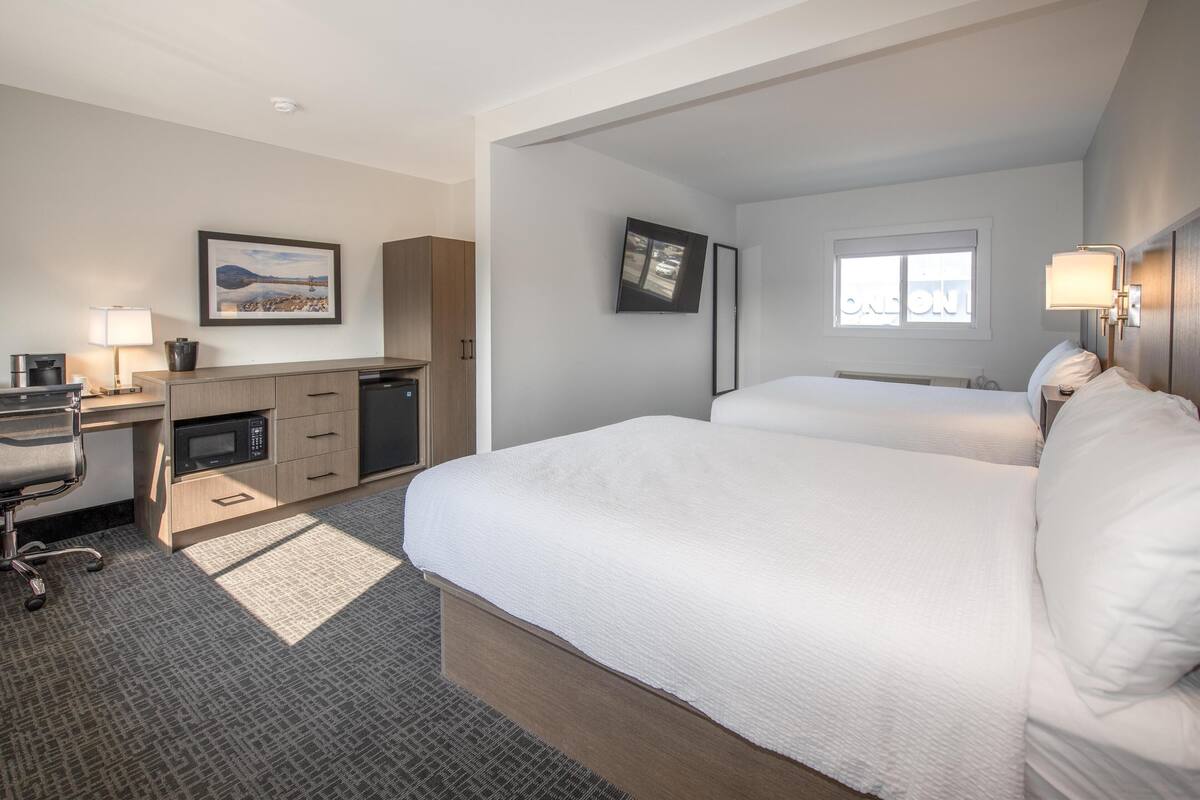 Una habitación de hotel con cama, escritorio, microondas y televisión.