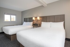 A hotel room with two beds, a nightstand, and a window with blinds.