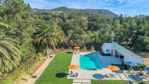 Ein Garten mit Swimmingpool, Liegestühlen und Sonnenschirmen.
