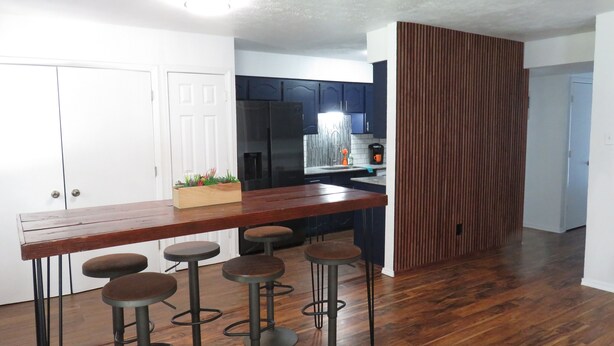 A kitchen with a wooden bar, stools, and a potted plant.