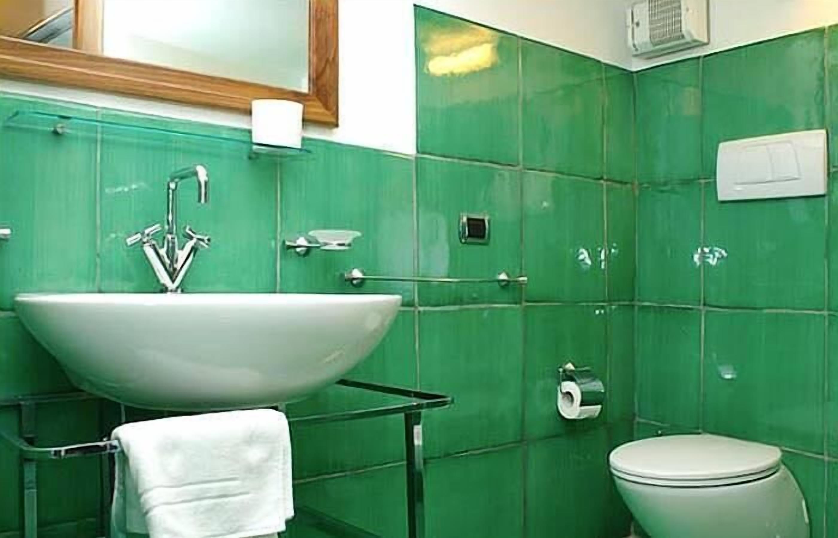 A bathroom with a large white sink, a mirror above it, and a toilet.