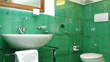 A bathroom with a large white sink, a mirror above it, and a toilet.