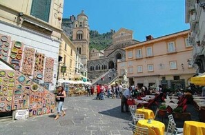 A bustling street with outdoor seating and a variety of shops. - AMALFIVACATION.IT Loft with private terrace with Pool (AMALFI)