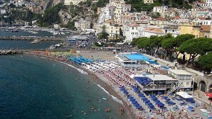 Un pueblo costero con playa, barcos y edificios.