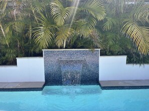 A swimming pool with a mosaic wall and palm trees in the background.