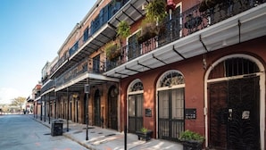 Una hilera de edificios históricos con ventanales arqueados y balcones, una acera y una calle.