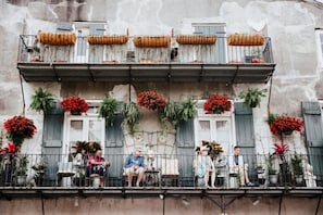 A balcony with potted plants and flowers, a railing, and a building facade.